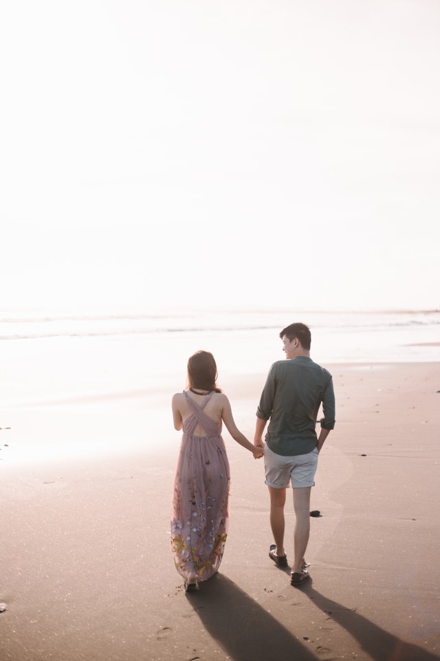 Pareja tomados de la mano y caminando juntos por la playa