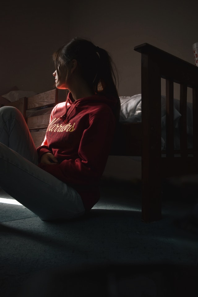 Woman with depression looking to the side, leaning on her bed