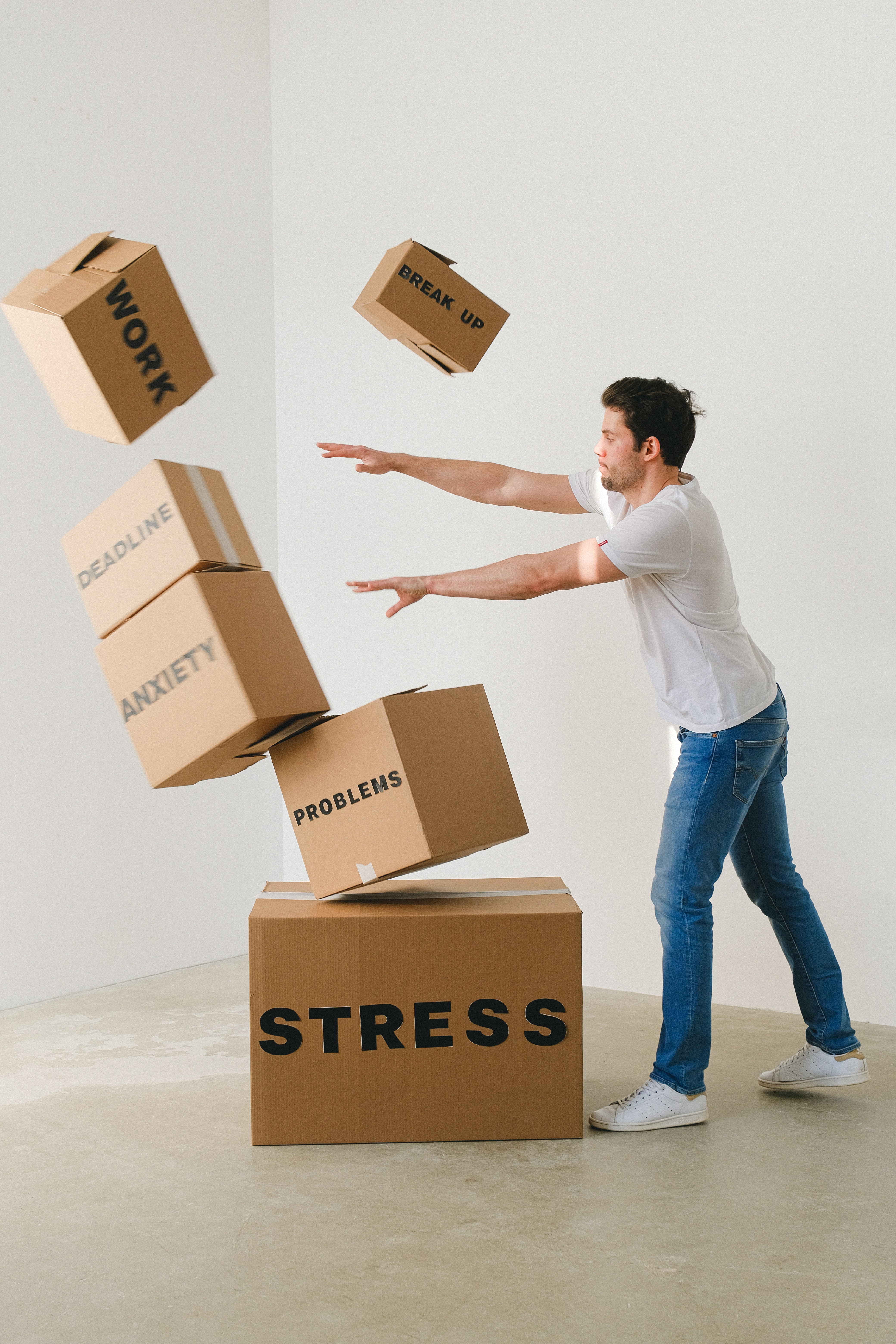 Boxes labeled with stress, work, and other things that can cause anxiety being knocked over by a man